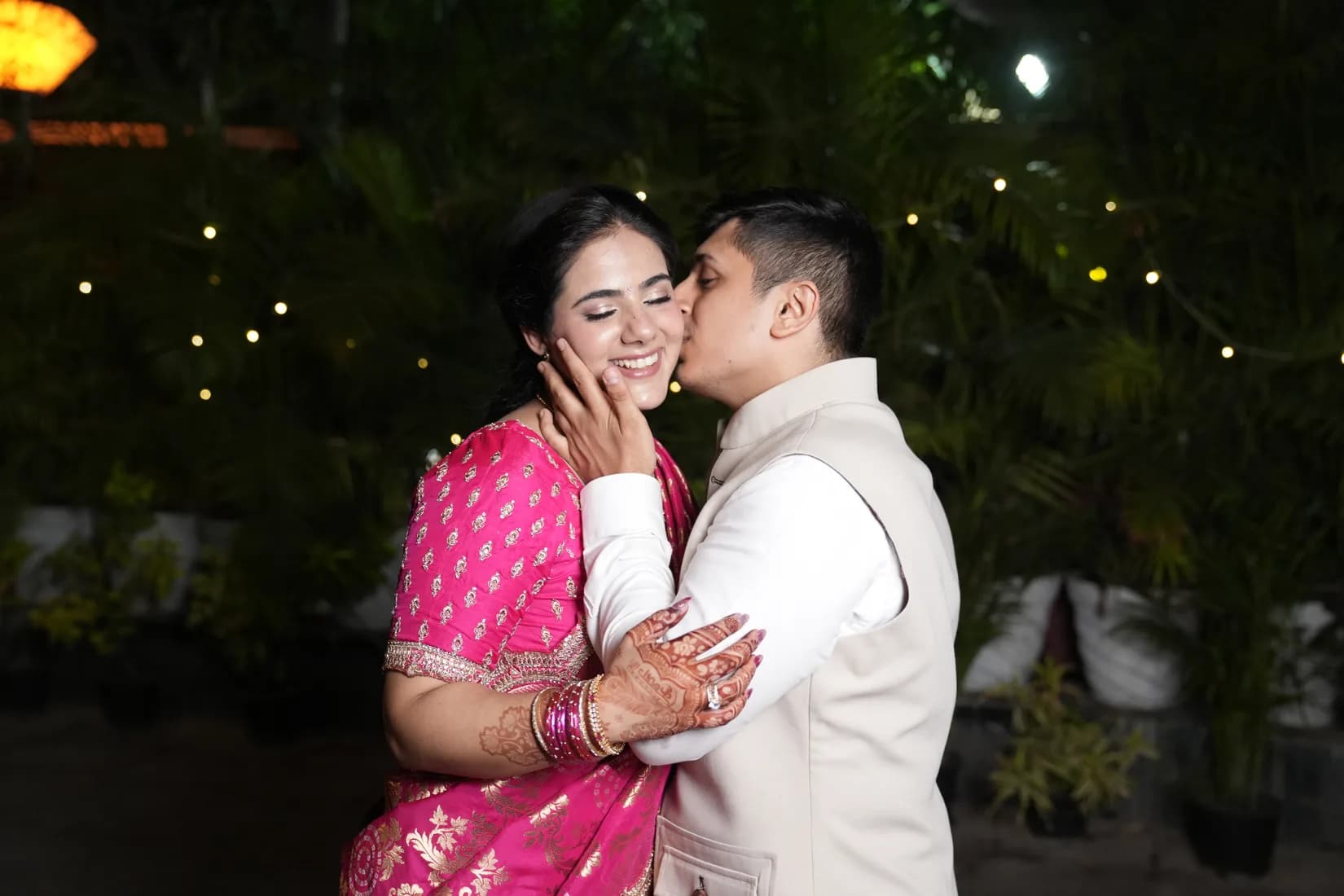 Bride in designer lehenga and groom in traditional sherwani at luxe hotel ballroom with dramatic lighting