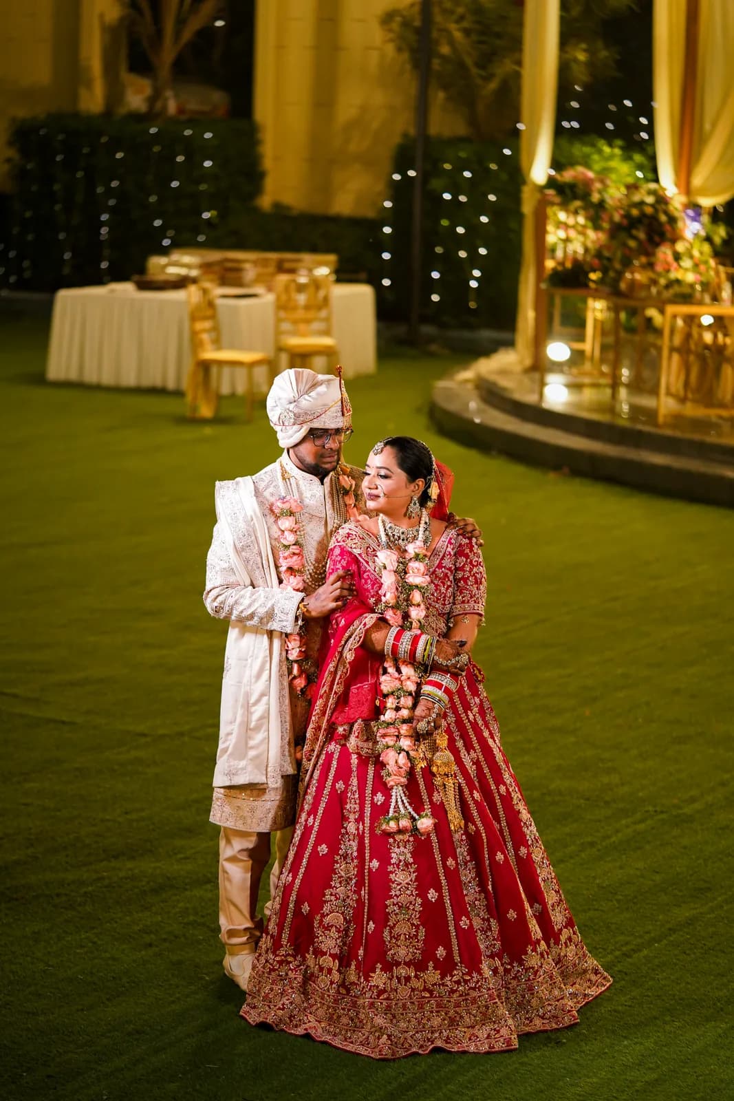 Couple in red wedding attire at an outdoor evening ceremony — Lens9 Studio, New Delhi