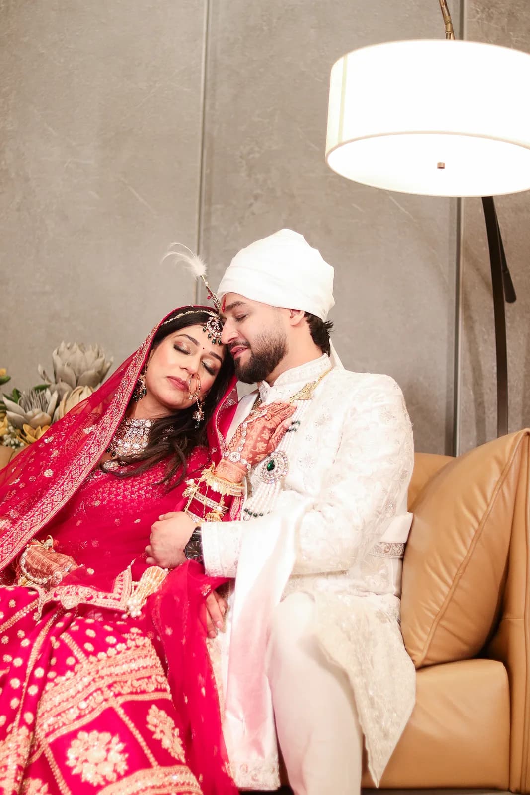 Seated couple in red and white wedding outfits — Lens9 Studio, New Delhi